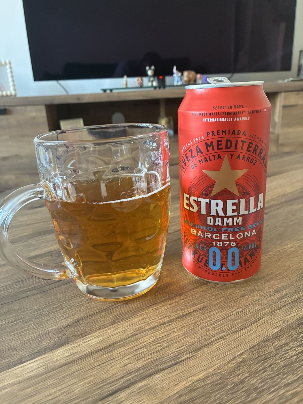 Estrella Damm 0.0 poured into a dimpled glass mug next to the can