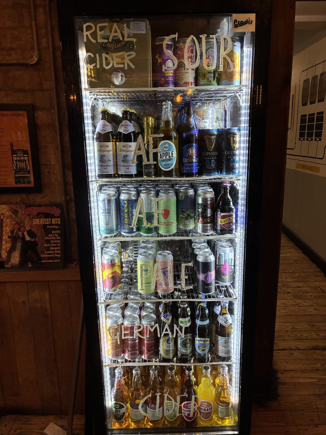 A tap room fridge with hand-labelled shelves of alcohol-free beer — AF, German, pale and cider sections